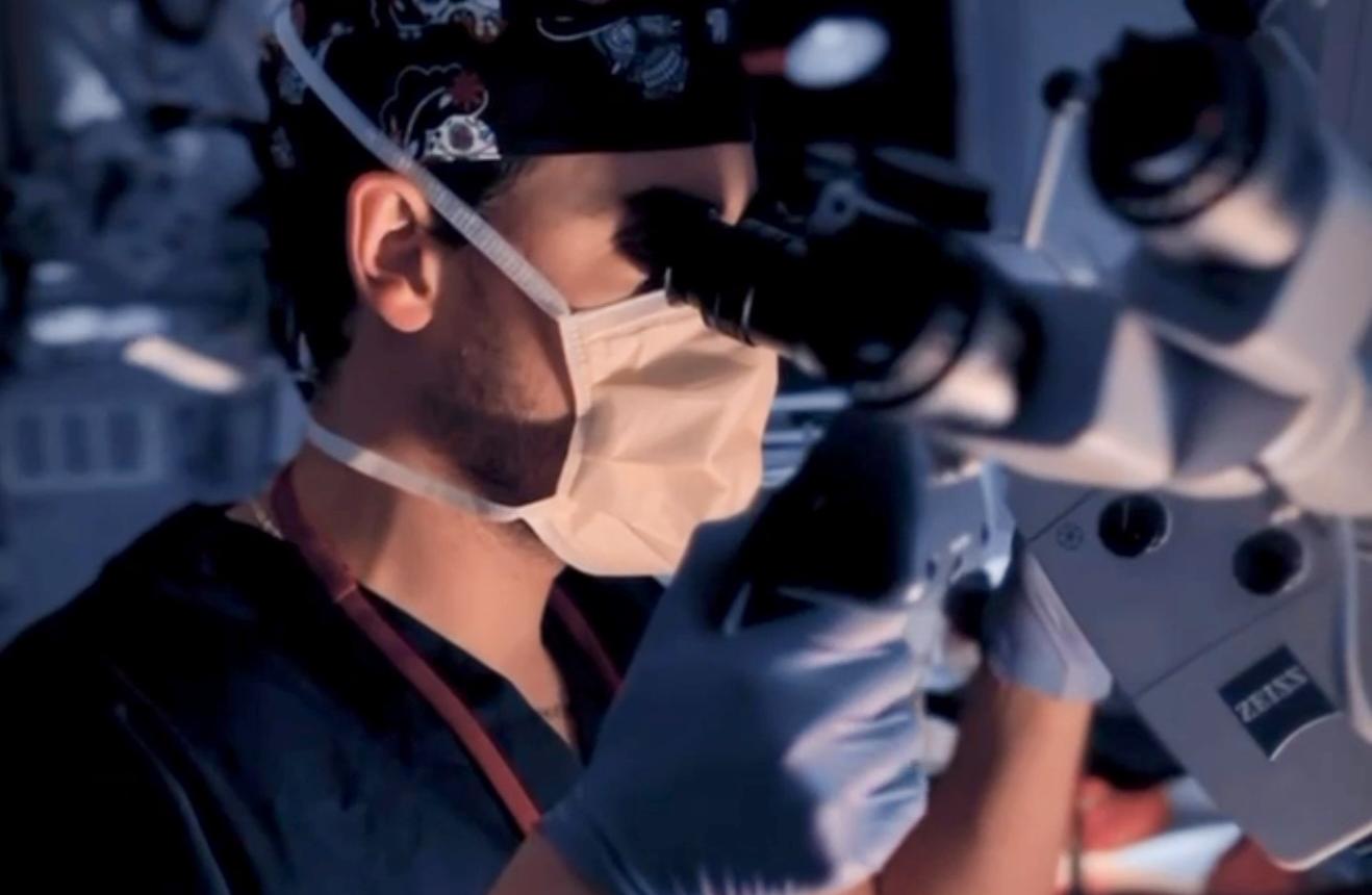Photo of Fellow Adjusting a Surgical Microscope within the NITC